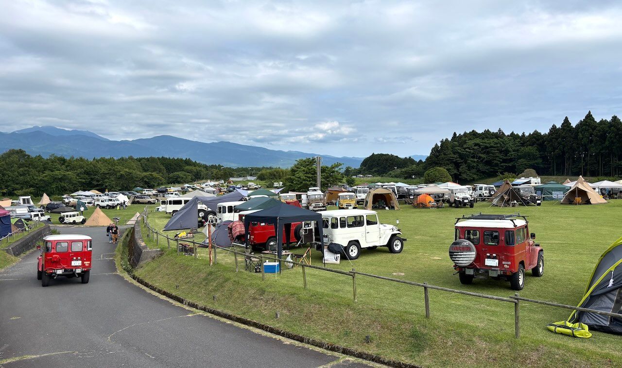 Around 440 Land Cruiser 40 Series lined up across the grass at a campsite at the foot of Mt. Fuji.
