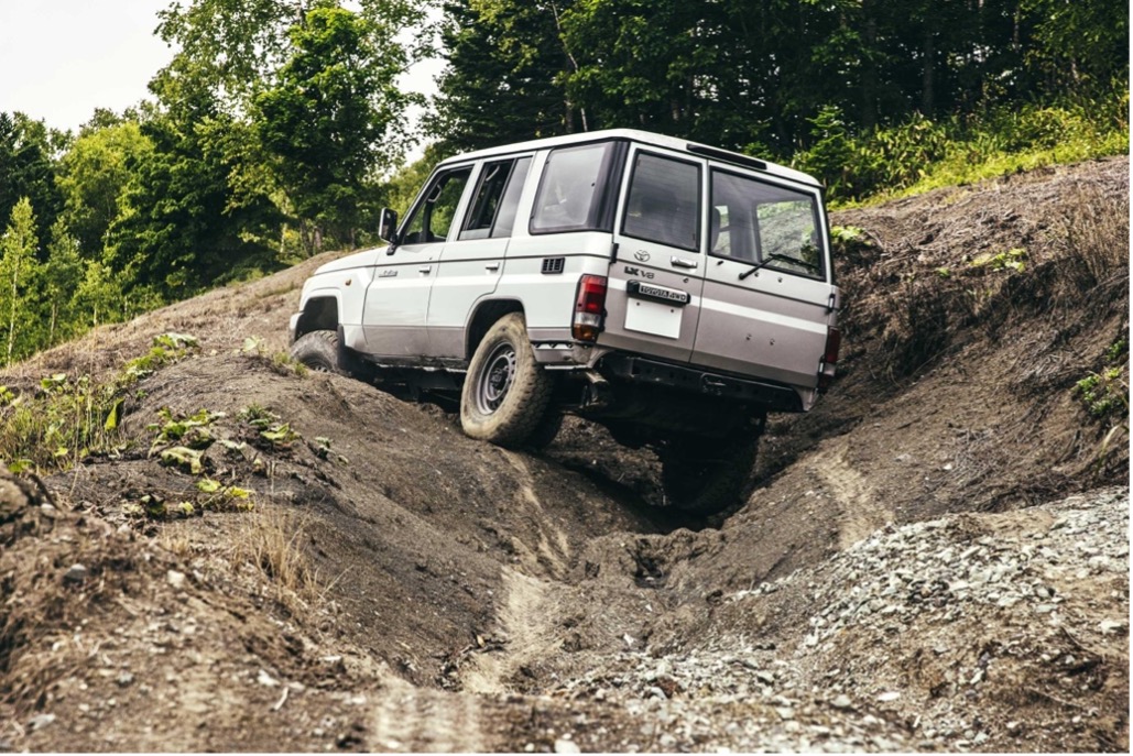 The Land Cruiser 70 Series climbs a hill with huge bumps and furrows. The suspension strokes keep the tires in contact with the ground